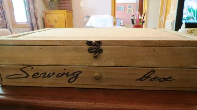 A beautiful wooden sewing box with a padded hinged lid, and drawer beneath.